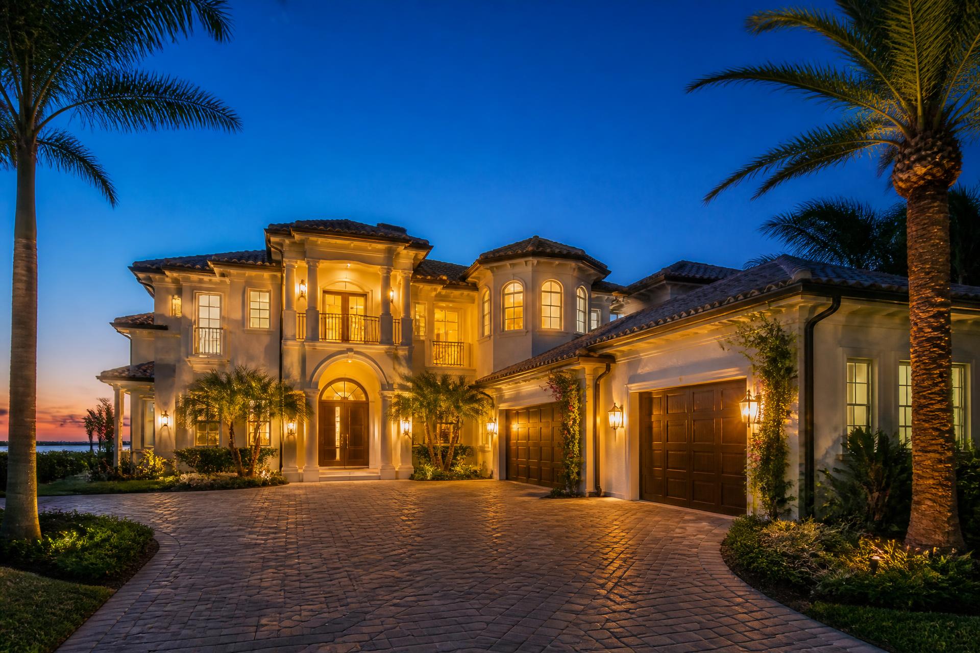 Florida home at dusk with lit windows and palm trees, protected by HomeCrew home watch in Stuart, FL